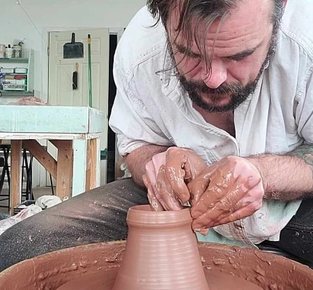 Man using potter's wheel to create a ceramic pot
