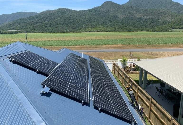 Solar panels on a roof in Cairns with mountains in the background.