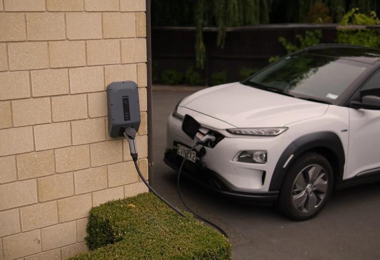 A white SUV is plugged into a Hielscher Electrical electric charger, utilizing solar energy.