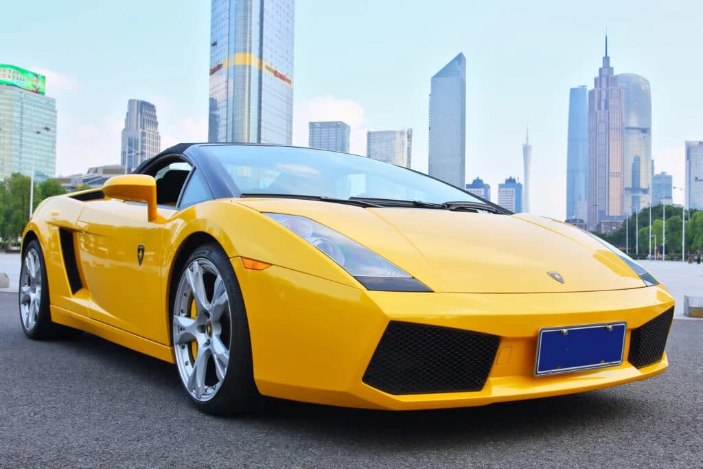 A dreamy sports car is parked in front of a city.